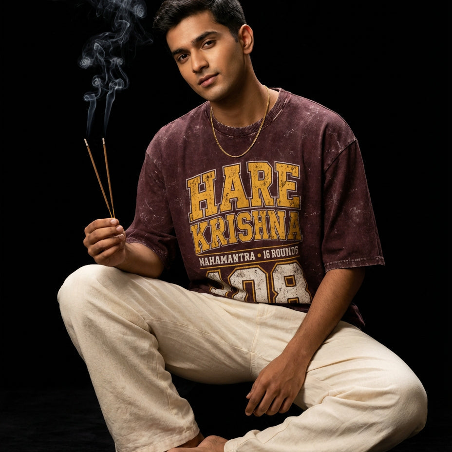 Man wearing a 'Hare Krishna' t-shirt holding incense sticks against a black background