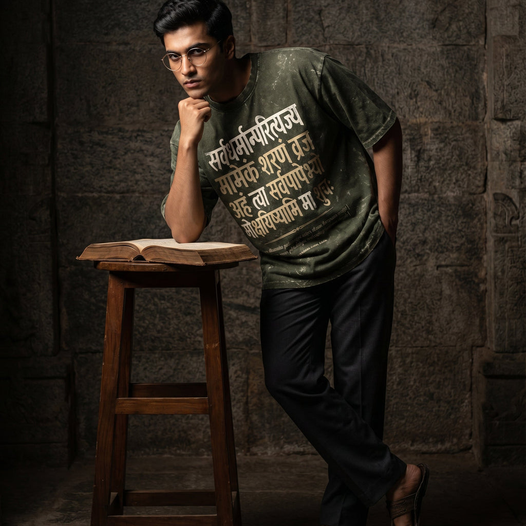 Man wearing a green t-shirt with text, leaning against a stone wall with an open book on a stool.